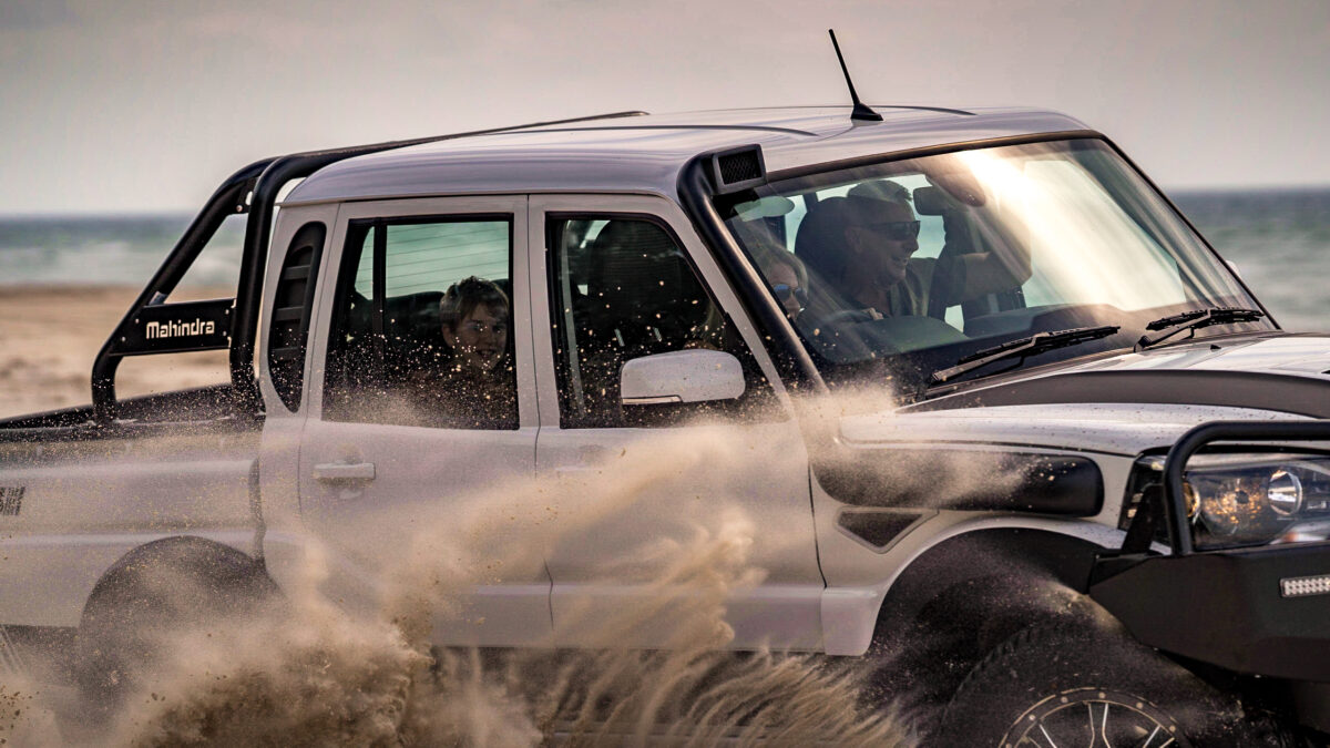 Off-road adventure: Mahindra pick-up navigating the beach sands with passengers on board.